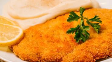 Carne à milanesa, com rodela de limão e molho